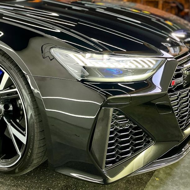 Close-up of a sleek black sports car with distinctive headlights and alloy wheels.