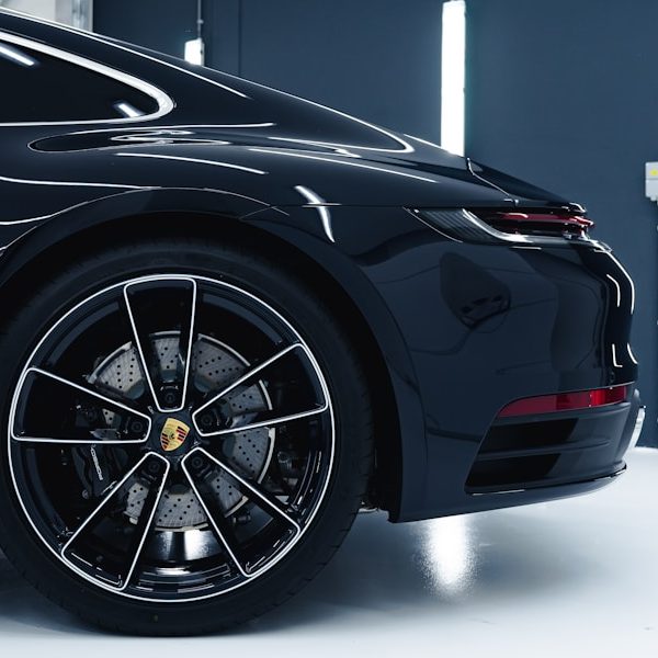 Side view of a black sports car with a slick design and intricate wheel details.